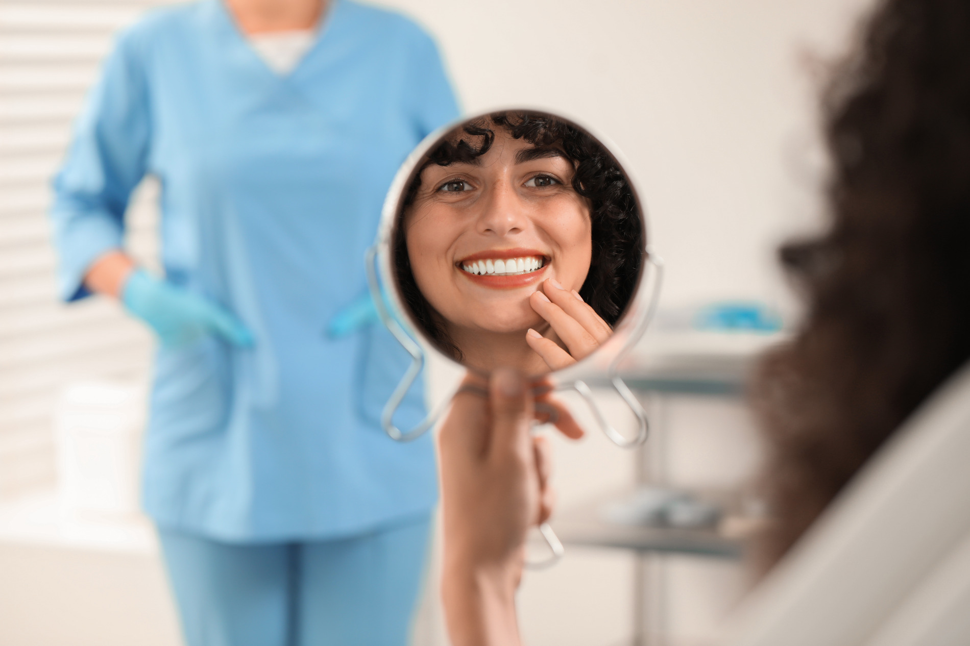 Woman looking in a mirror after her teeth whitening treatment in Golden CO