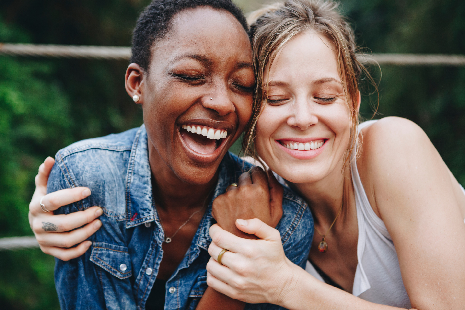Two women hug and smile with striaghtened teeth from Invisalign in Golden CO